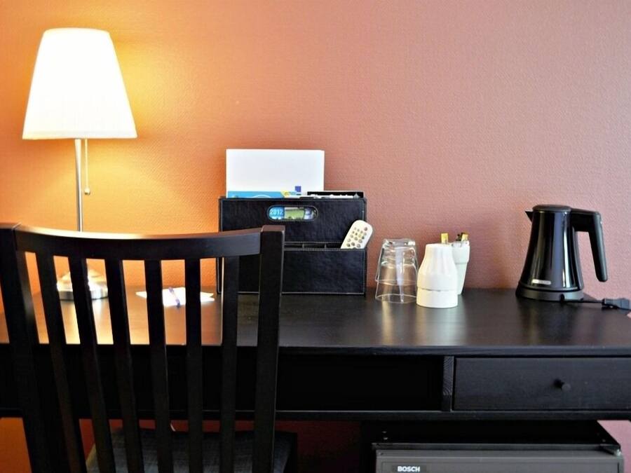 Un bureau avec une lampe, une mallette noire, une machine à café et une chaise.