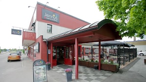 A hotel named Jennys with a red exterior and a covered outdoor seating area. - Jennys Hotell och Restaurang (Arvika)