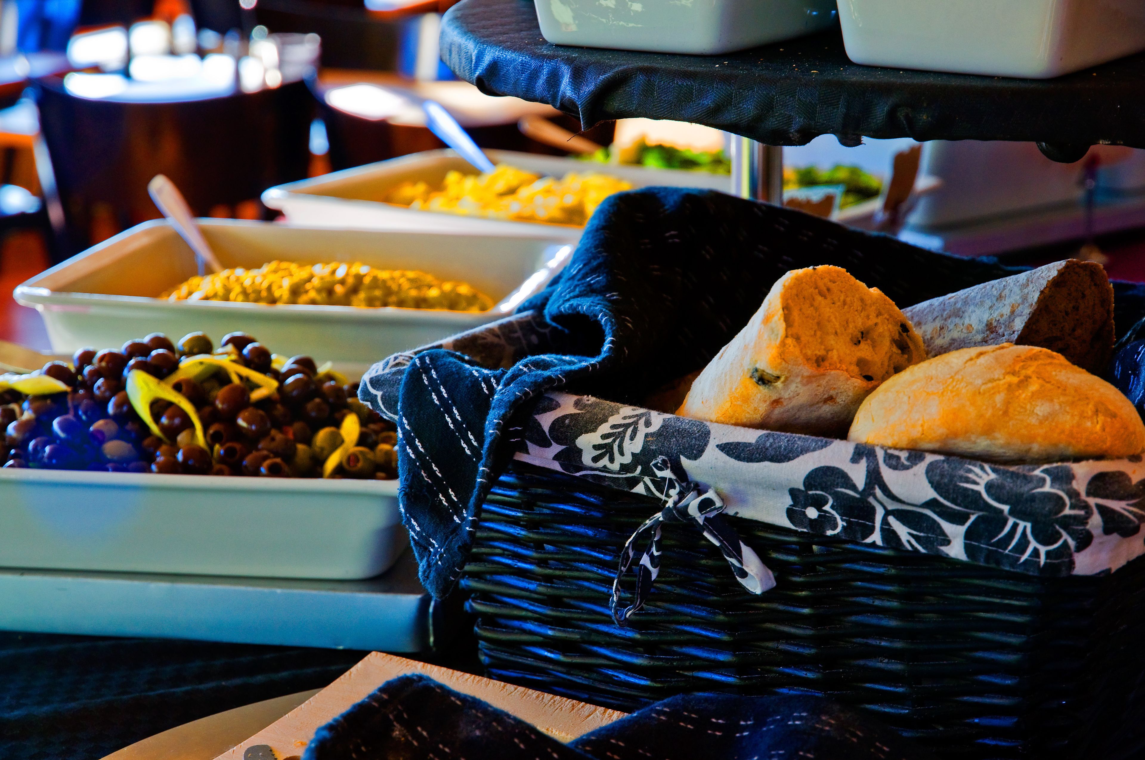 Une table de buffet garnie de divers plats et un panier contenant des petits pains.