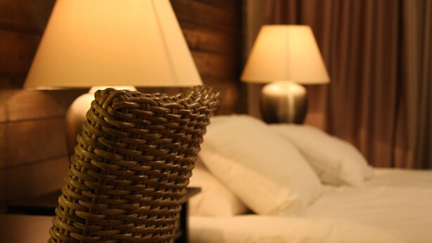 A bed with white linens, a woven basket, and two lamps on bedside tables. - Jennys Hotell och Restaurang (Arvika)