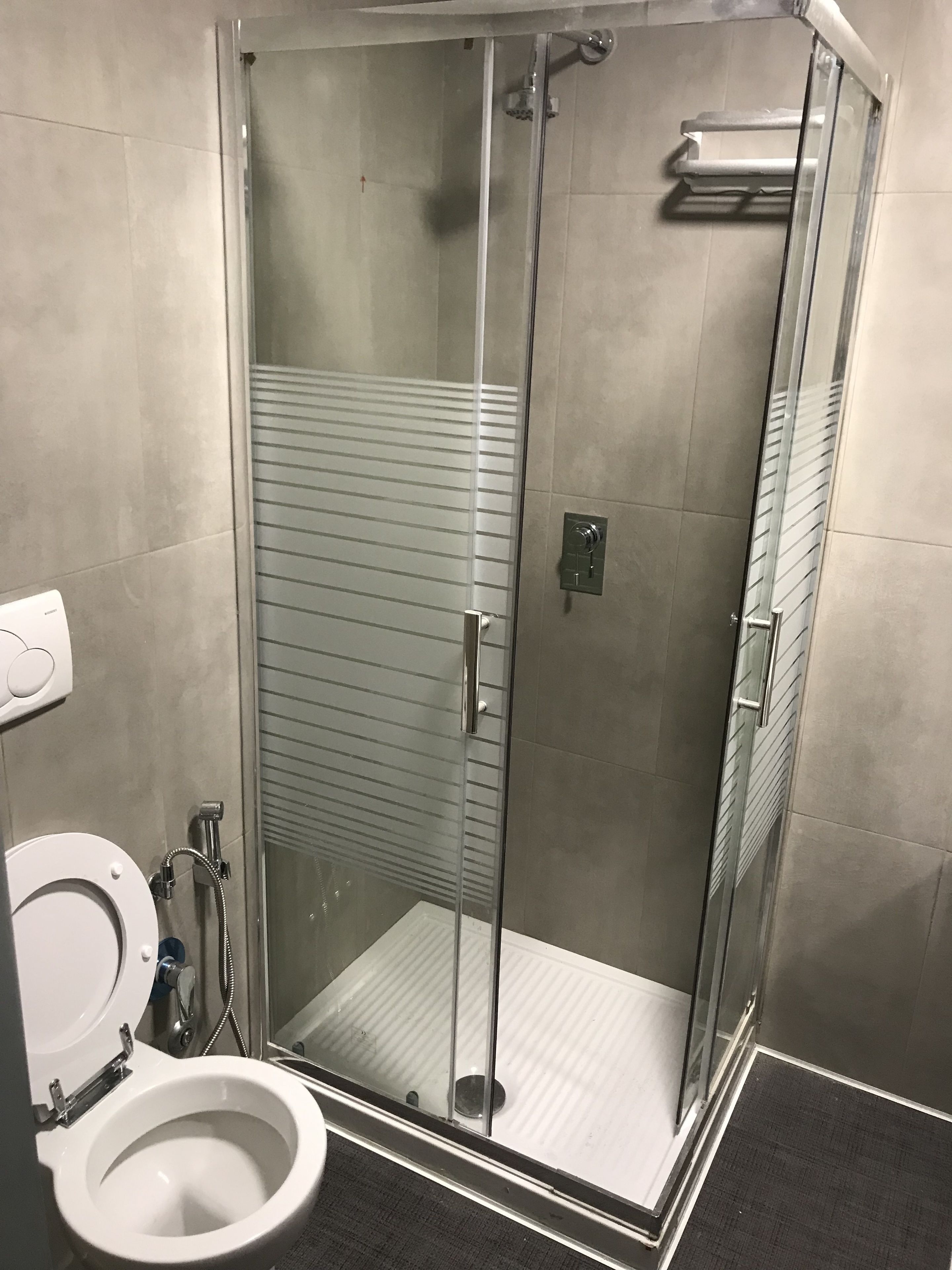 A glass-enclosed shower stall with a toilet to the left.