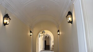 A hallway with white walls, a decorative ceiling, and two wall-mounted lanterns. - Dimora Frattina (Rome)