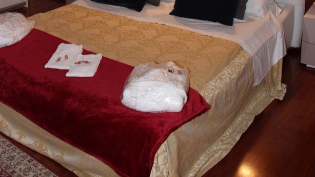 Habitació d'hotel amb un llit gran, una paret vermella i un quadre de mans.