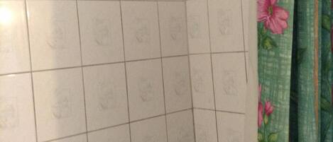 Un área de ducha con azulejos y una cortina con motivos florales.