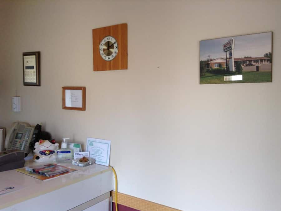 A room with a desk, a clock, a framed certificate, and a motel sign on the wall.