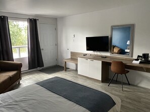 A hotel room with a bed, a desk with a computer, a TV, and a chair. - Restaurant-Motel le Rond-Point (Métabetchouan)