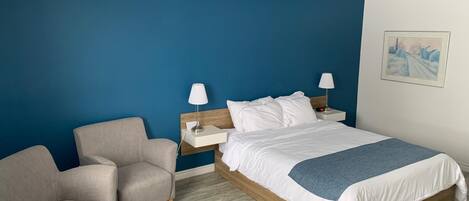 A hotel room with a bed, two bedside tables, a chair, and a painting on the wall.