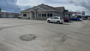 Un edificio con garaje, estacionamiento y una gasolinera al fondo.