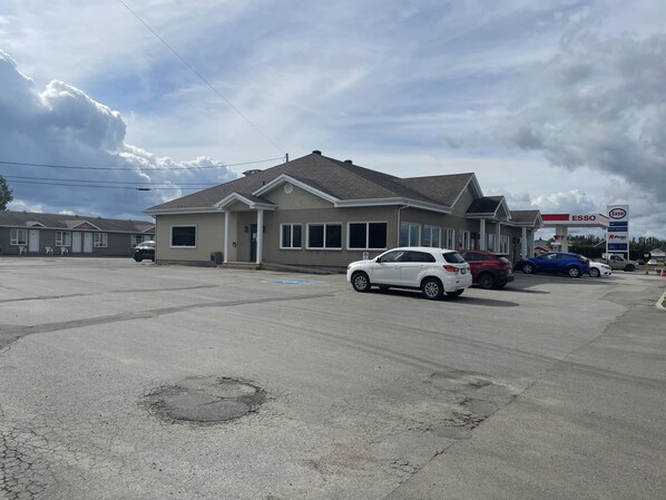 A building with a garage, a parking lot, and a gas station in the background.