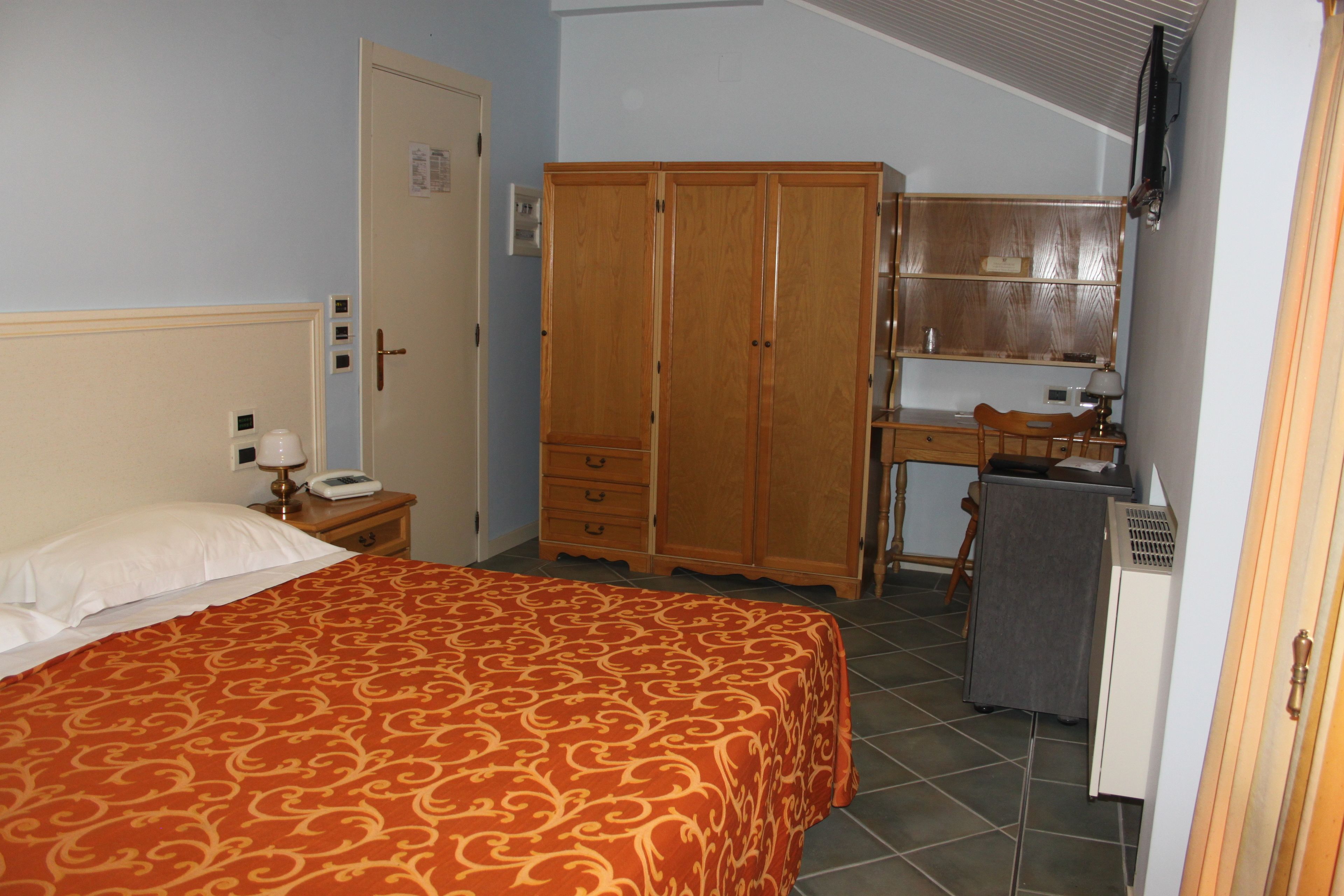 Ein Schlafzimmer mit Bett, Kleiderschrank, Schreibtisch und Stuhl.
