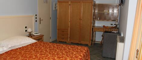 Un dormitorio con cama, armario, escritorio y silla.