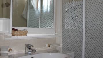 A bathroom with a white sink, a mirror, and a shower enclosure.