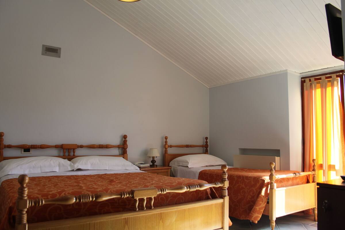 A hotel room with two wooden beds, a nightstand, a dresser, and a ceiling vent.