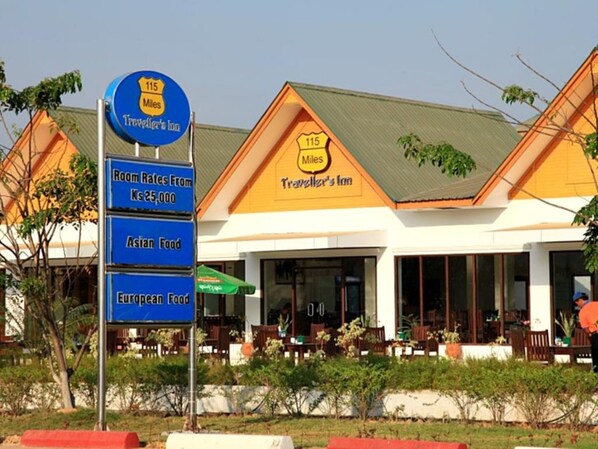 A traveler's inn with a sign indicating room rates from $25,000, Asian and European food options, and a 115 miles distance marker. - KMA 115 Miles Hotel (Phyu)
