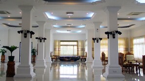 Un hall d’entrée spacieux, doté de hauts plafonds, de grandes colonnes et d’un espace salon central.