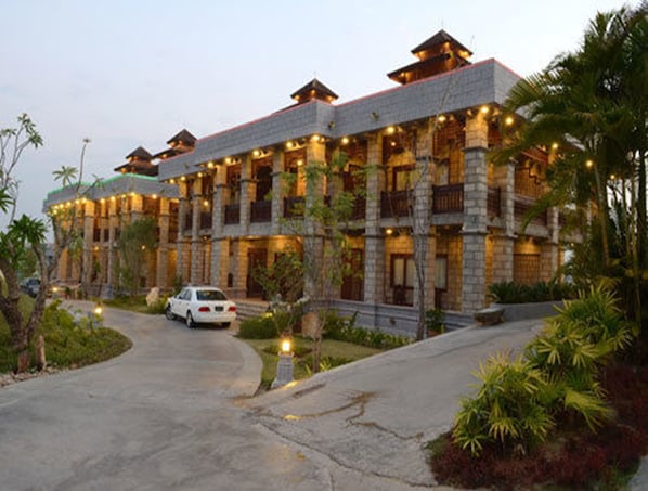 Un hotel de varios pisos con un estilo arquitectónico tradicional, que cuenta con una entrada curva y un paisaje exuberante.