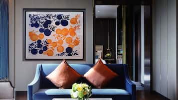 A modern living room with a blue sofa, two brown cushions, and a vase of flowers on a marble coffee table.