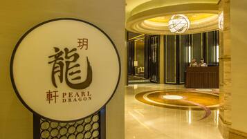A hotel lobby with a reception desk, a circular decorative floor pattern, and a large illuminated sign with Chinese characters.