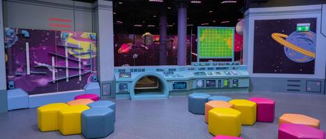 A space-themed play area with colorful seating and control panels.