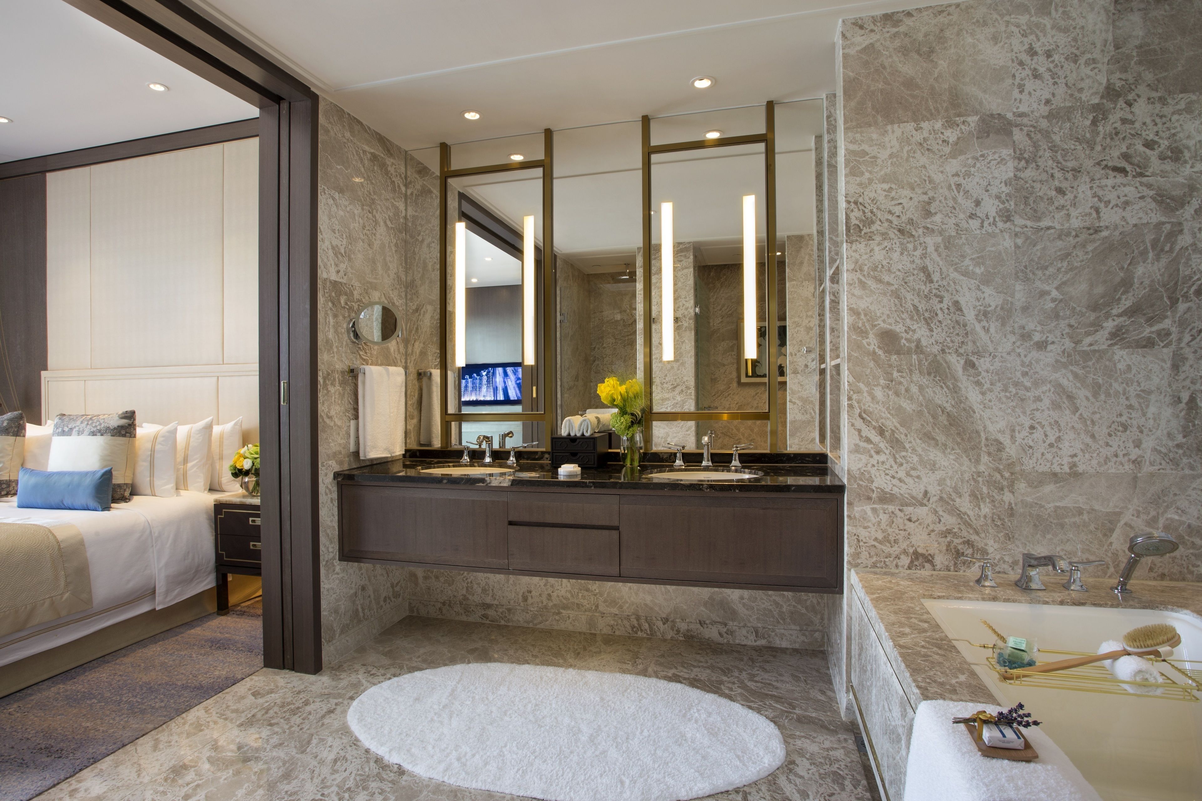 A modern bathroom with a marble sink, a bathtub, and a large mirror.
