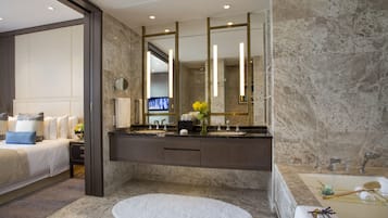 Un baño moderno con lavamanos de mármol, una bañera y un espejo grande.