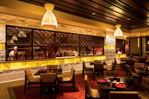 Un restaurante con área de bar, diversas opciones de asientos y vista a la cocina.
