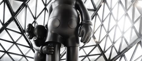 A sculpture of a character with a rounded body and circular features, set against a geometric metal structure.