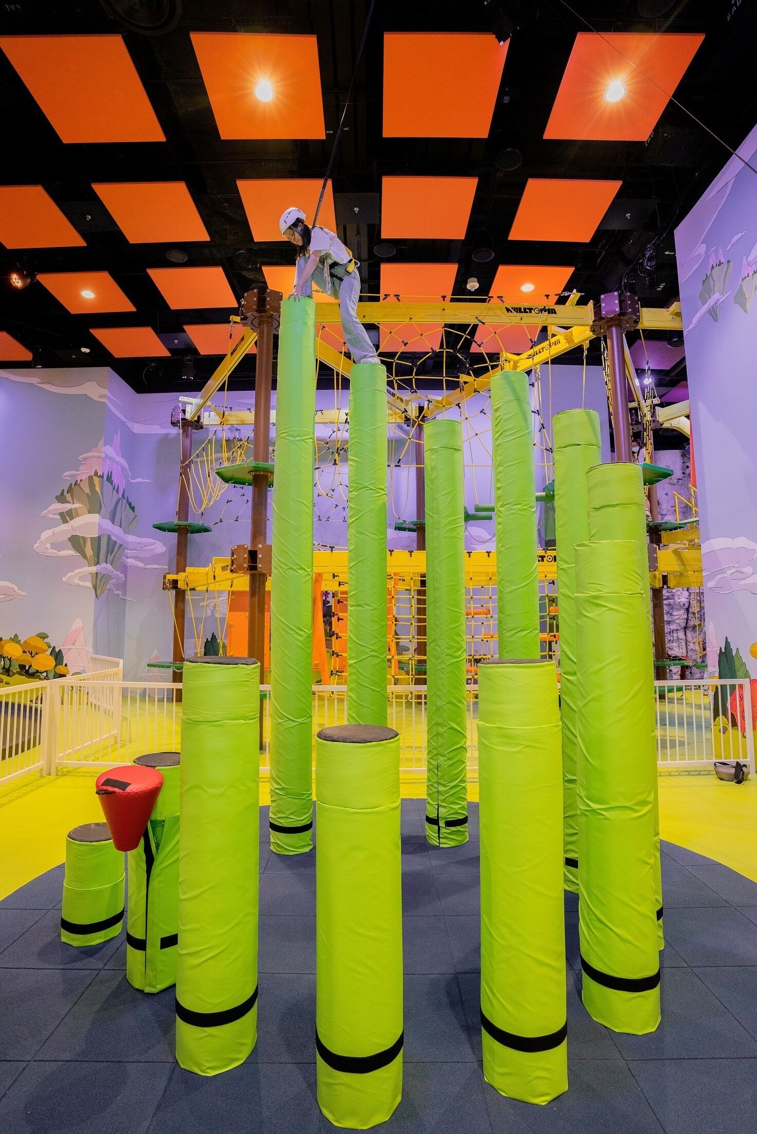 A play area with a climbing structure, padded obstacles, and a safety railing.