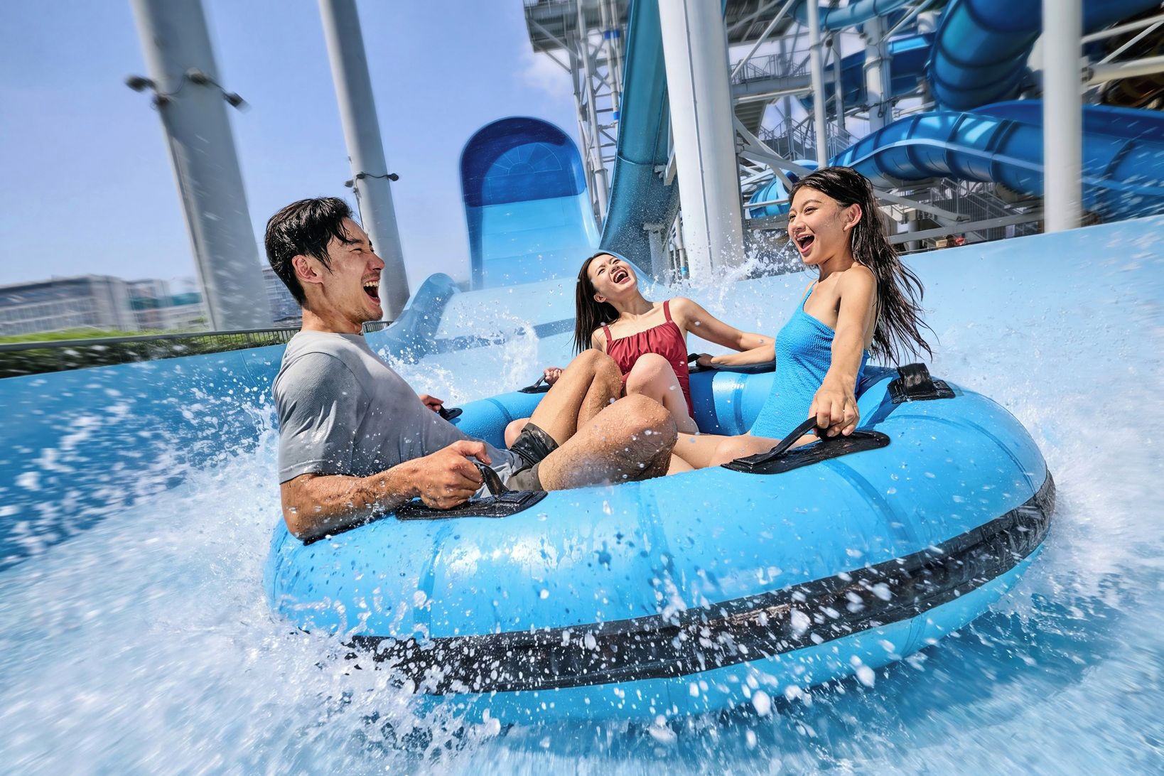Three people on a blue water ride with water splashing around them.