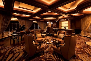 A luxurious lobby with a grand piano, plush seating, a bar area, and ornate ceiling details.