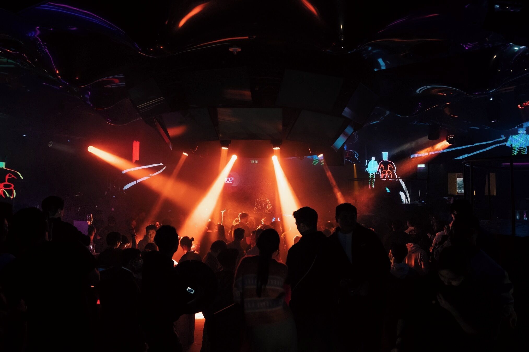 A crowded indoor venue with a stage and bright stage lighting.