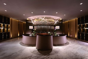 A modern reception area with a central desk, two side desks, and a decorative light fixture above.