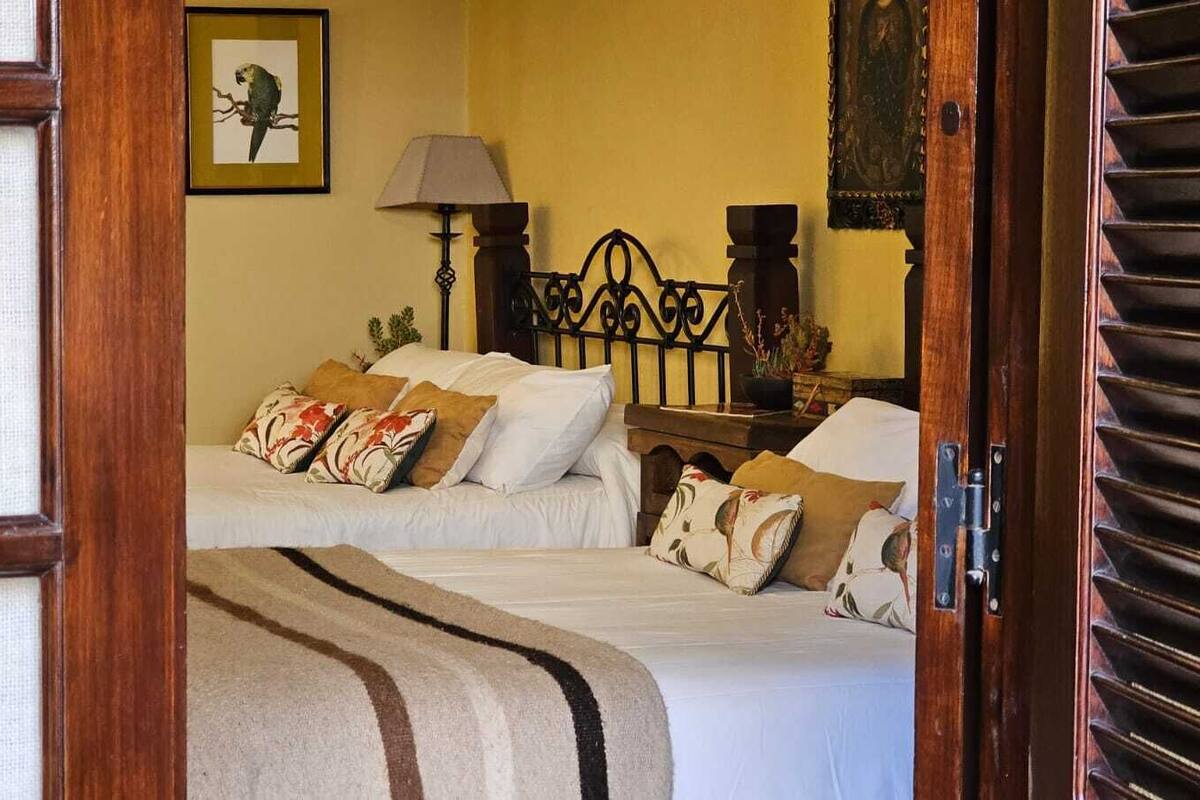 A hotel room with two beds, a nightstand, a lamp, and a framed picture on the wall.