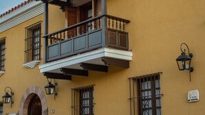 Un edificio con balcón, base de piedra y una puerta en arco.