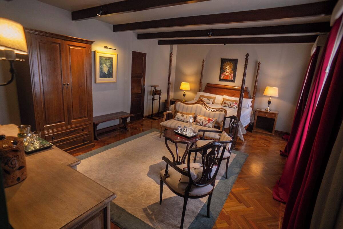 A traditional room with a bed, wooden furniture, and a chandelier.