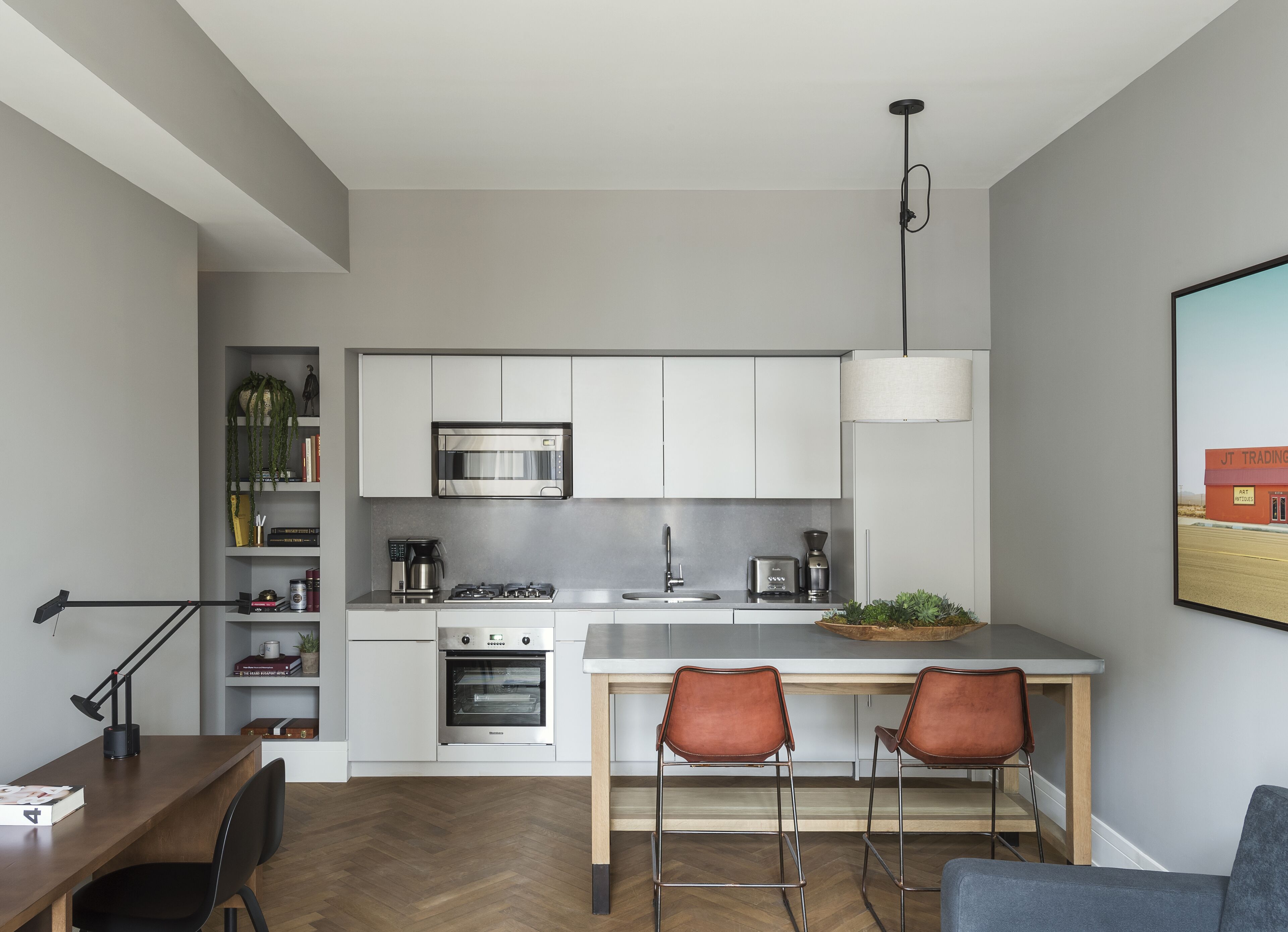 A modern kitchen with white cabinets, stainless steel appliances, and a wooden island with bar stools.