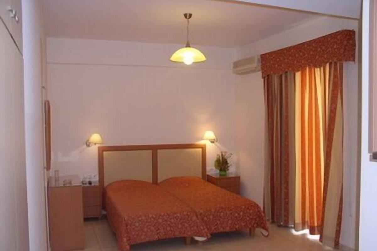 A bedroom with a bed, two bedside tables, a lamp, and curtains.