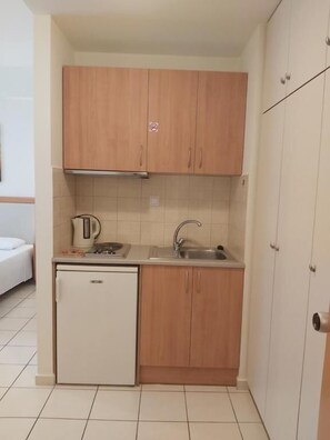 A compact kitchen with wooden cabinets, a built-in oven, and a sink. - Evagellina (Rethymno)