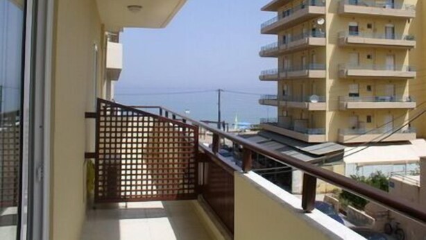 A multi-story residential building with balconies, a wooden fence, and a clear view of the sea. - Evagellina (Rethymno)