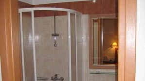 A bathroom with a glass-enclosed shower, a pedestal sink, and a mirror above the sink. - Evagellina (Rethymno)