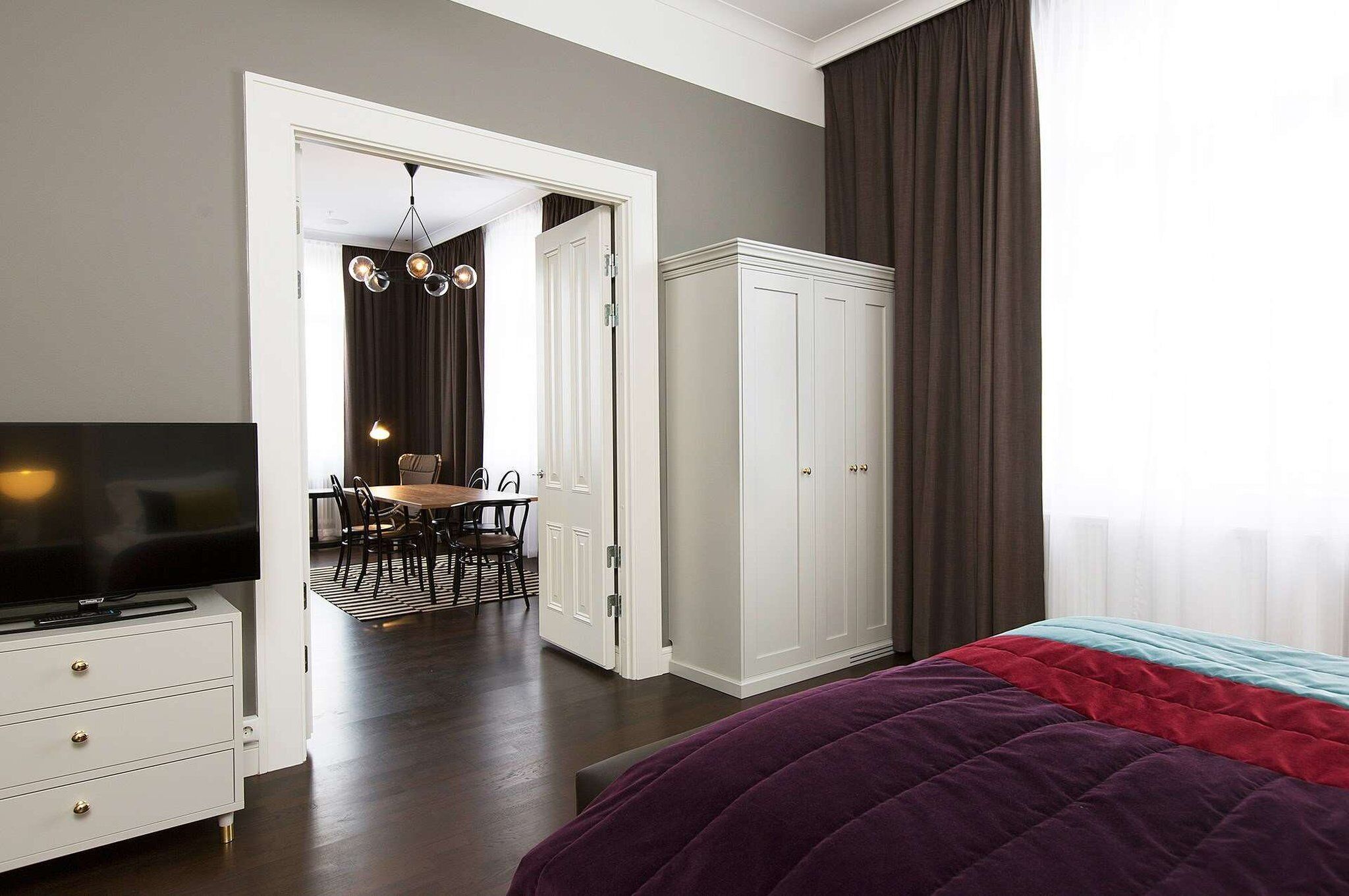 Une chambre à coucher comprenant un lit, une télévision, une armoire et un coin repas avec des chaises et une table.