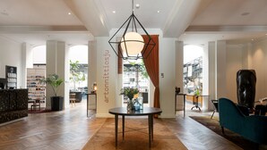 A spacious lobby with a central round table, a reception desk, and a large window with curtains. - Elite Hotel Mimer (Umea)