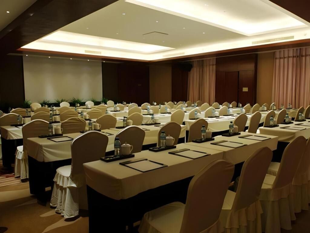 A conference room with long tables, chairs, and a ceiling light fixture.