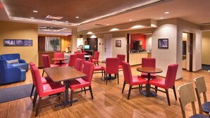 Um saguão de hotel com assentos vermelhos e azuis, um balcão de recepção e uma área de bar.