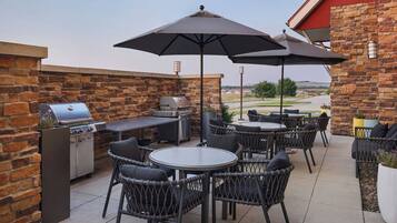 Une terrasse extérieure équipée d’un barbecue, de sièges et offrant une vue sur le paysage.