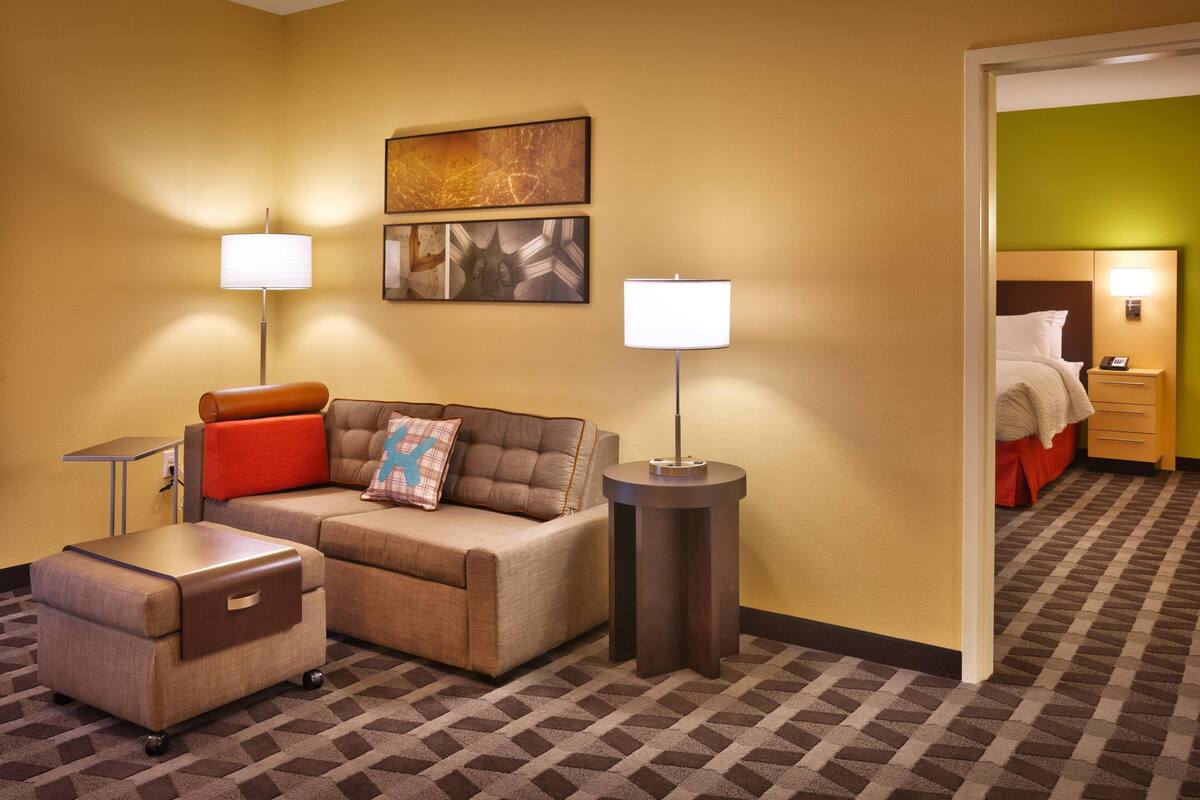 Une chambre d’hôtel avec un canapé, une petite table, une lampe et un miroir.