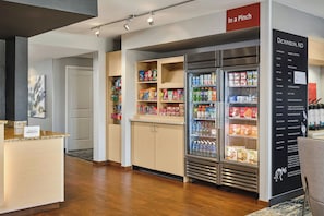 Un vestíbulo de hotel con una estación de autoservicio para bebidas, una recepción y una pared con información local.