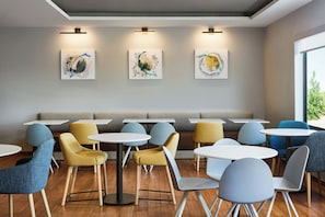 Een modern café interieur met ronde tafels, zachte zitplaatsen en kunst aan de muren.