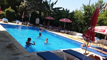 Una piscina al aire libre, sombrillas, sillones reclinables de piscina