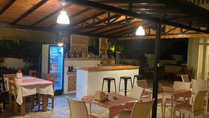 Un restaurante con terraza, una zona de bar y un refrigerador lleno de bebidas.
